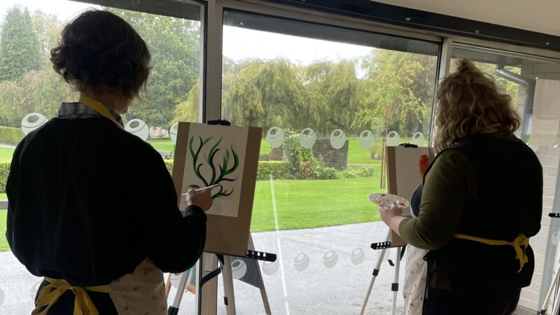 Mindful Art in the Park participants painting indoors, overlooking the park