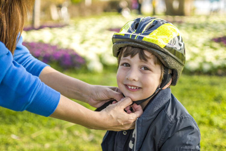 Boy on bike having helmet strapped on (Getty Images)
