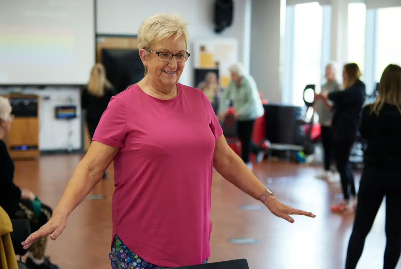 A woman in a pink t shirt taking part in a fitness class